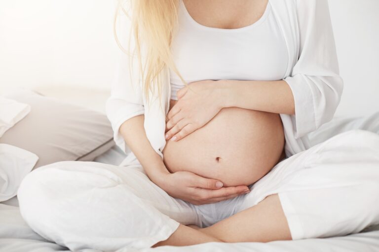 Schüßler Salze: Start Schüßler Salze: young pregnant soon be mother touching her belly sitting her bedroom afternoon pregnancy concept